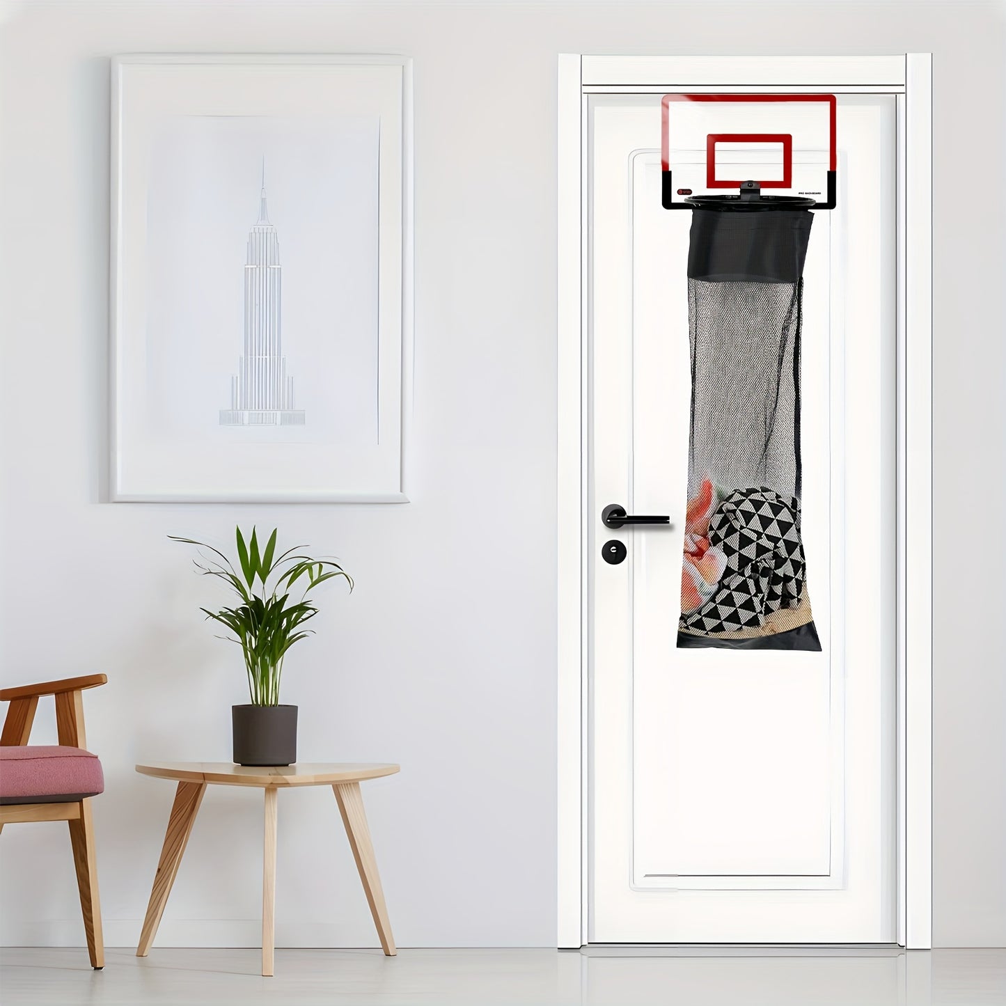 HighPeak SwishBin Laundry Hoop in red and black hanging over a white door with laundry inside in a modern room setting