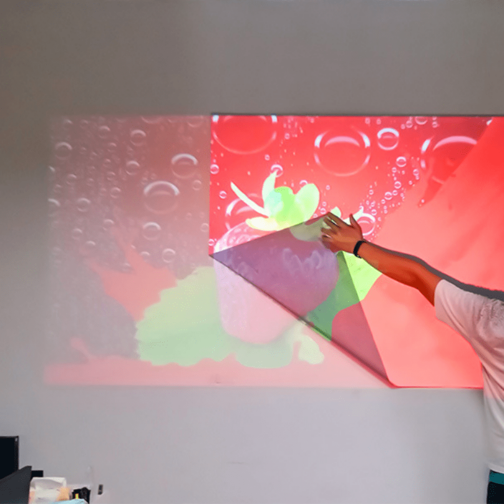 HighPeak ClarityBoost Projector Screen being peeled from wall showing vibrant red and green projections with anti-glare surface
