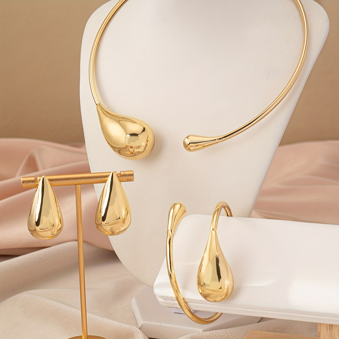 HighPeak Teardrop Jewelry Set in polished gold with necklace, bracelet, and earrings displayed on beige fabric background