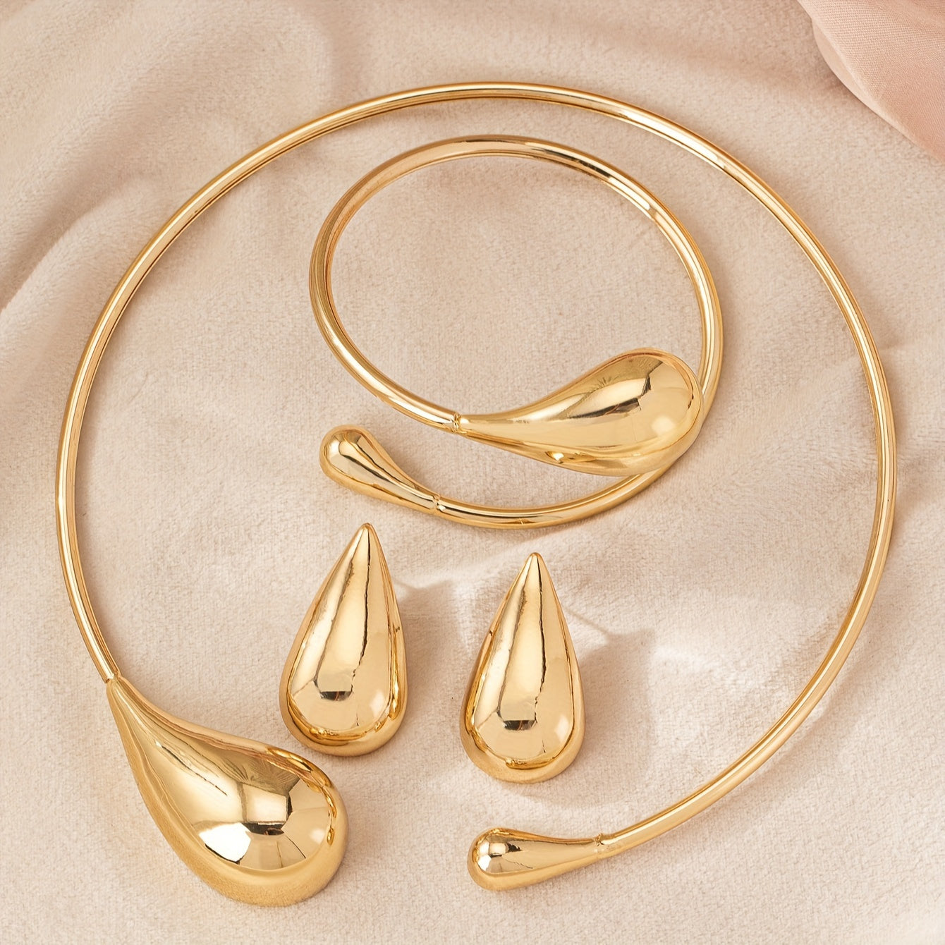 HighPeak Teardrop Jewelry Set in gold with sculpted necklace, bracelet, and earrings on beige fabric background