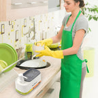 SoapMate™ manual soap dispenser with sponge holder in white and green on kitchen counter with woman washing dishes