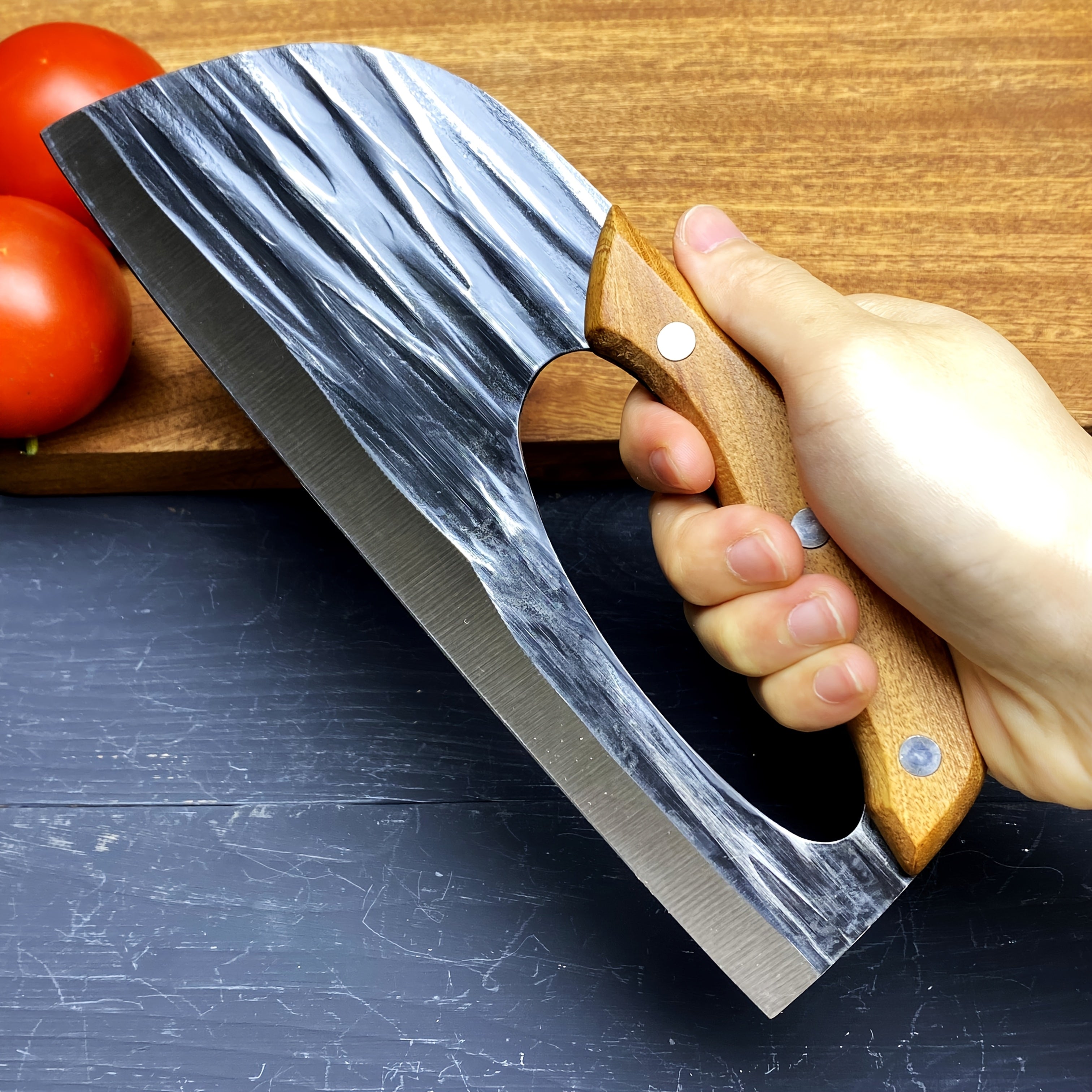 HighPeak Ergonomic Chef Knife with textured steel blade and wooden handle held for cutting on a black board next to tomatoes