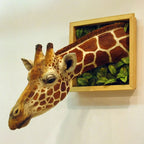 3D Giraffe Wall Sculpture extending from a golden frame with green foliage, viewed from the side.