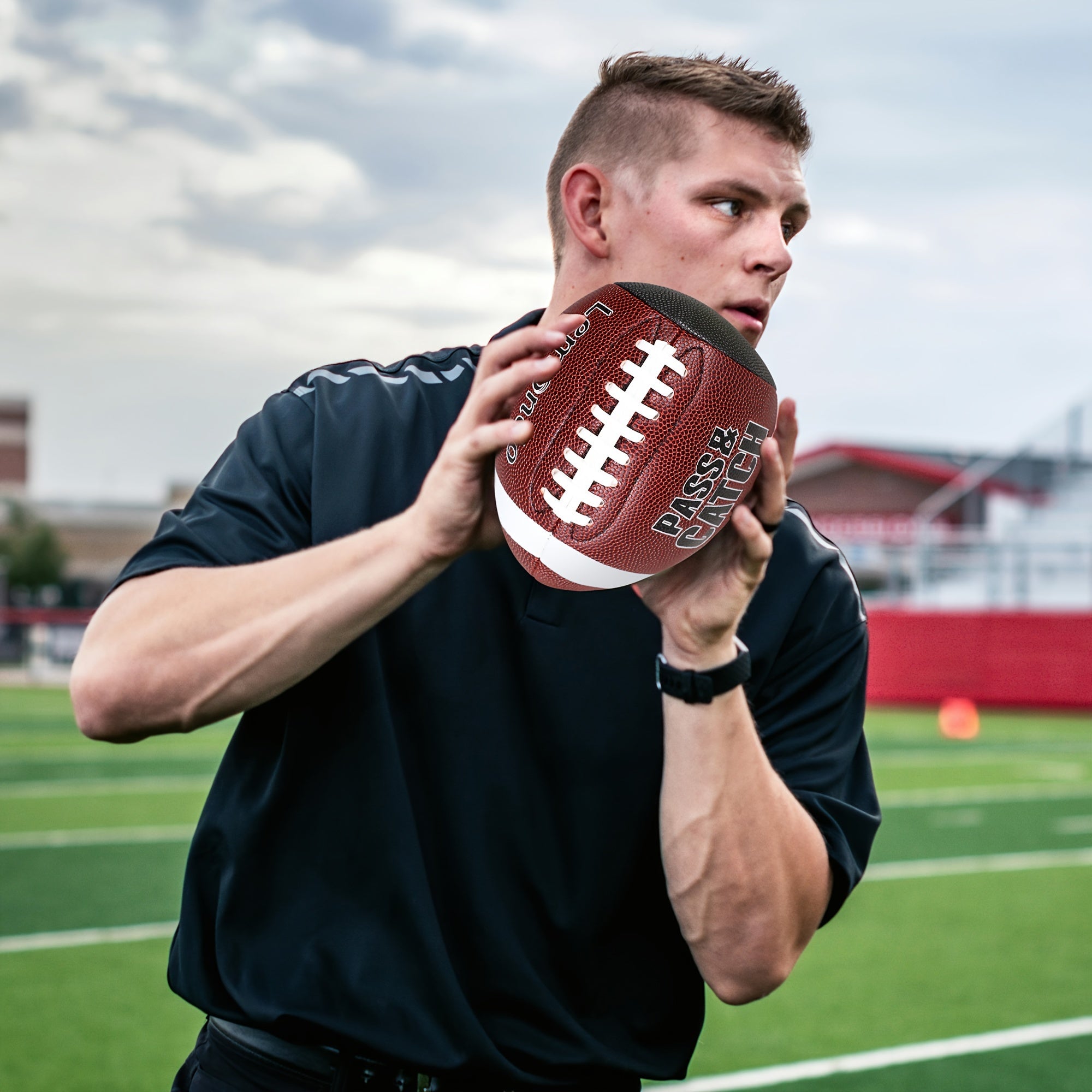 Man on football field holding GripEgg™ Trainer – PASS & CATCH Edition in brown with white laces ready to throw by HighPeak