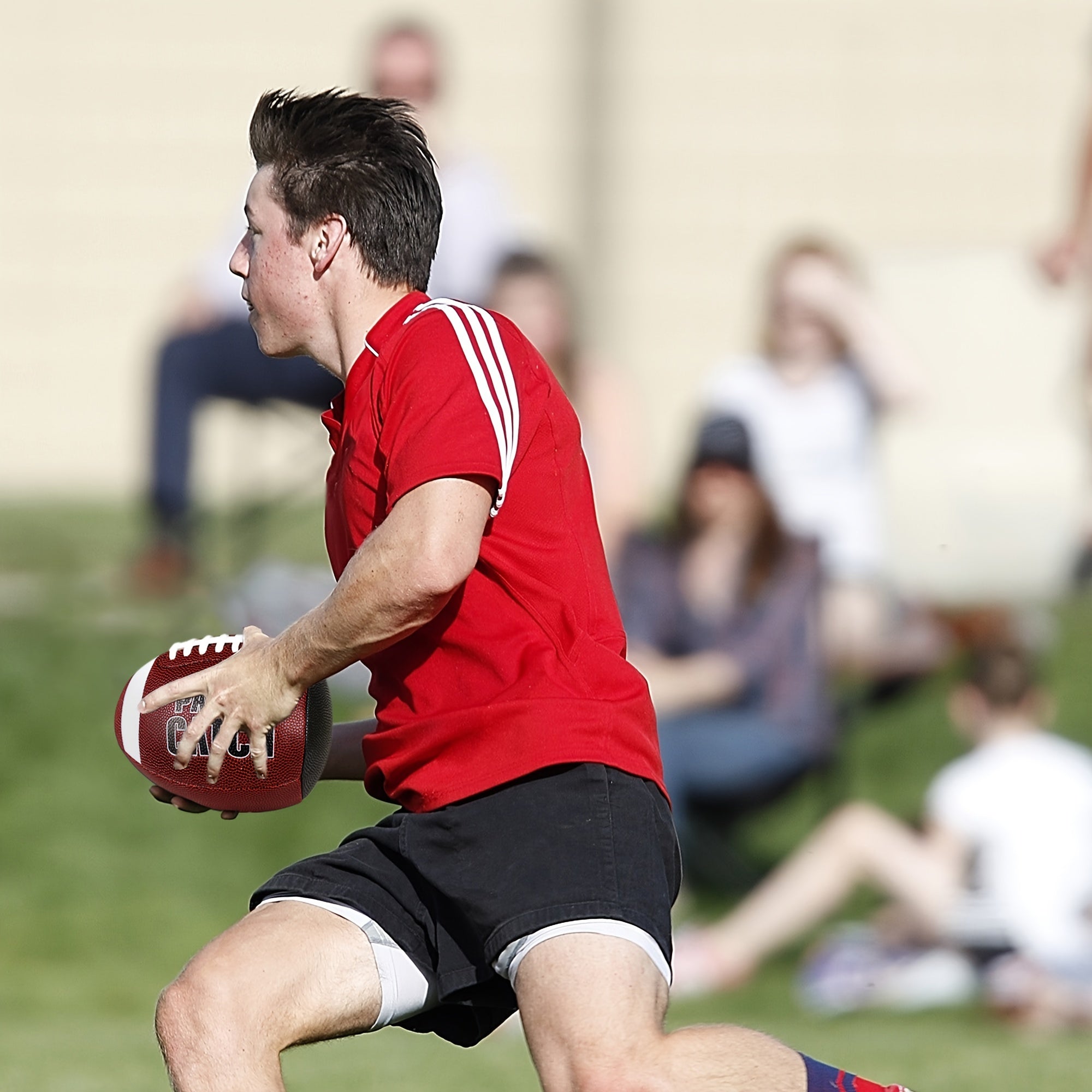 GripEgg™ Trainer – PASS & CATCH Edition held by a player in red shirt practicing solo football training in a grassy field