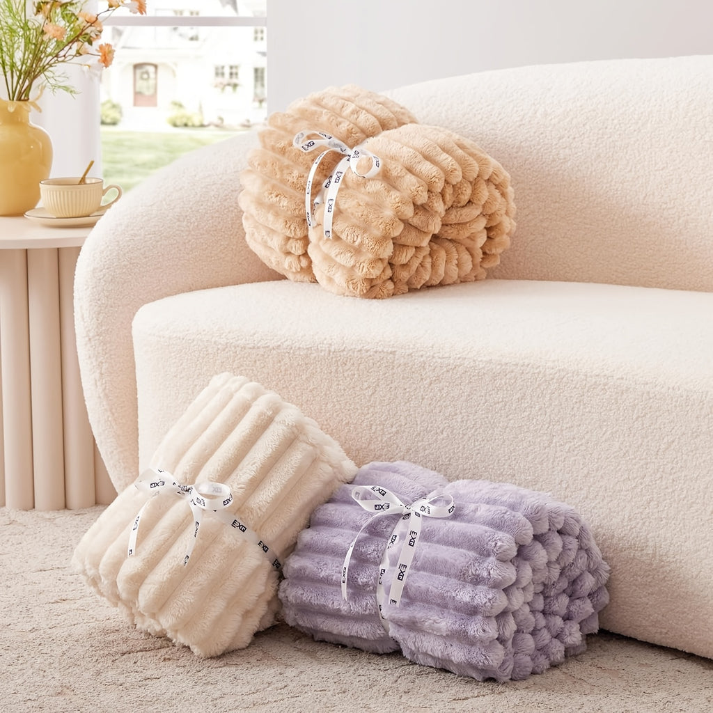 Cozy Fuzzy Blanket rolled and stacked in beige and lavender colors on white sofa, showcasing ribbed texture and plush fabric