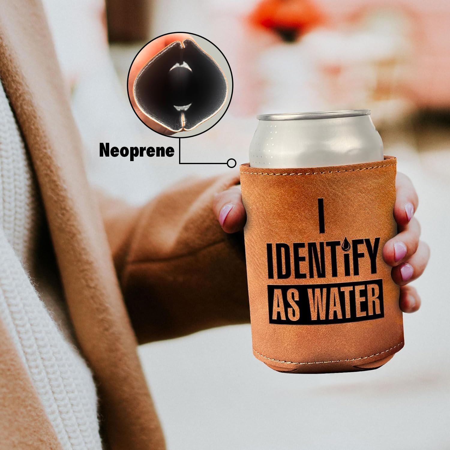 “I Identify As Water” Leather Can Cooler in tan faux leather with bold black text held in hand outdoors by HighPeak