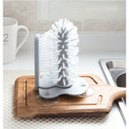 TwistClean™ - Cup & Glass Scrubber with white bristles mounted on wood board near sink, HighPeak cleaning tool