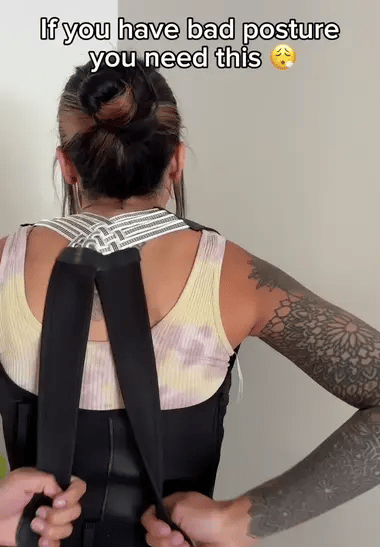 BackCrack Pro posture corrector shown on person wearing tank top, featuring black straps and adjustable cross-back design