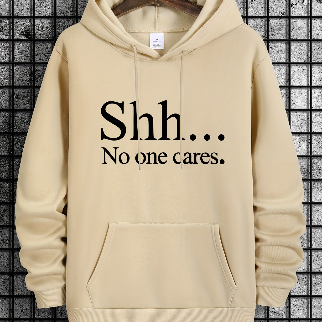 Beige pullover hoodie with "Shh... No One Cares" text design, featuring front kangaroo pocket and classic fit styling