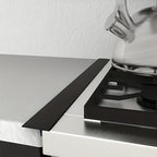 Black Kitchen Gap Guard installed between white counter and stove - seamless silicone gap cover for spill protection