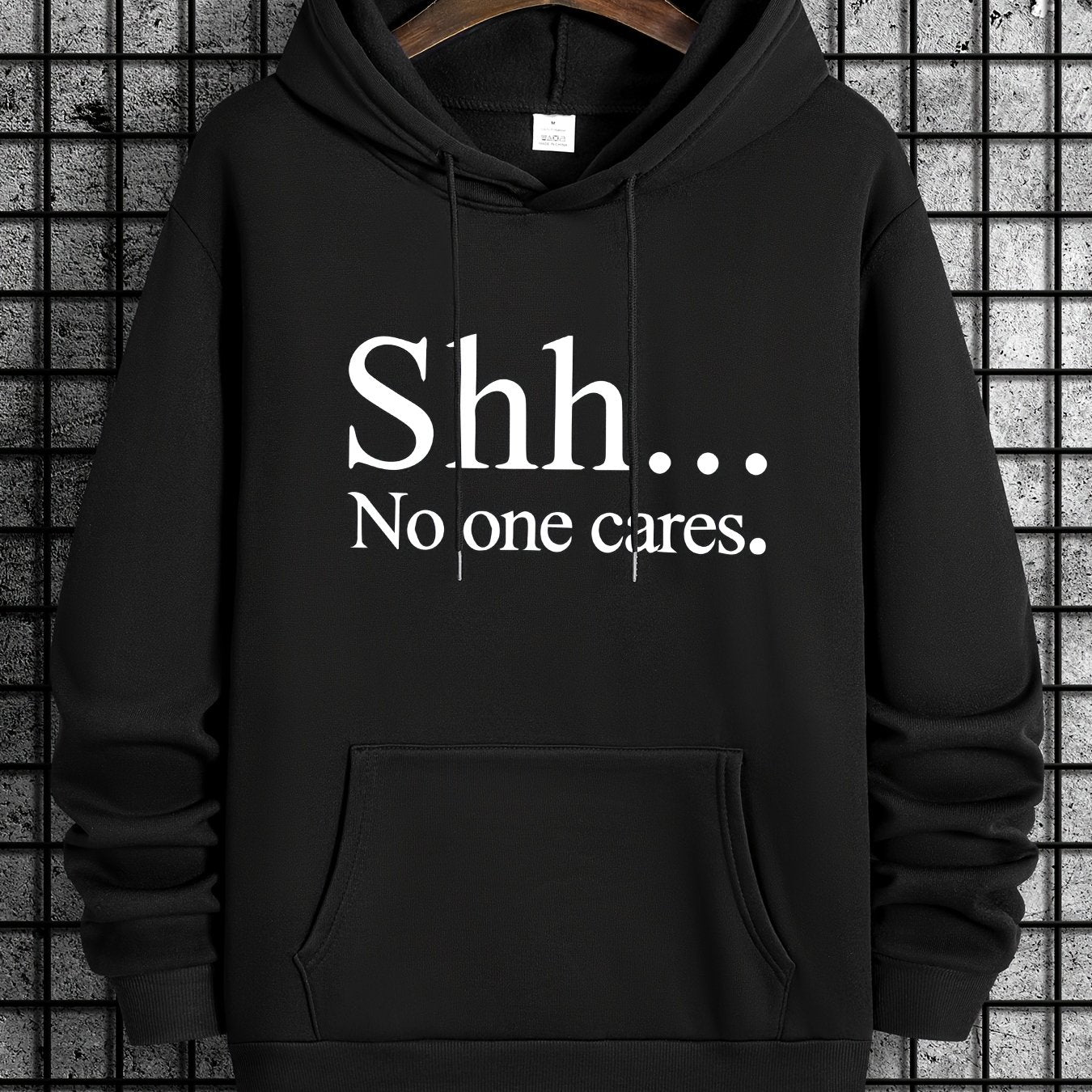 Black pullover hoodie with "Shh... No one cares" text in white letters, featuring front kangaroo pocket and classic design