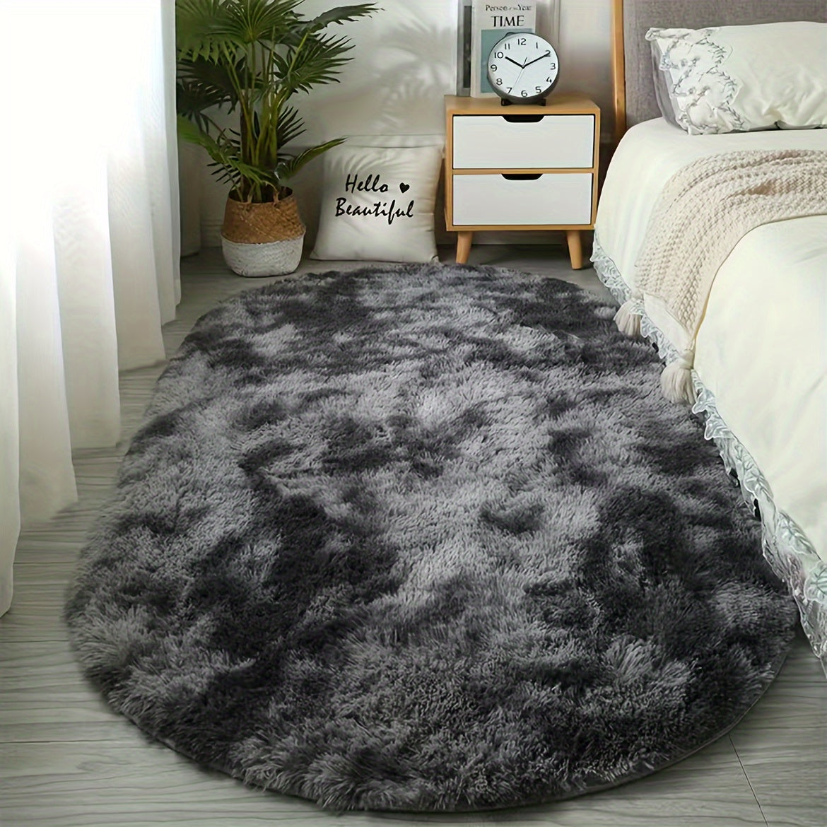 CloudLuxe Ultra Soft Plush oval area rug in charcoal gray beside bed, with plush shaggy texture on light wood flooring