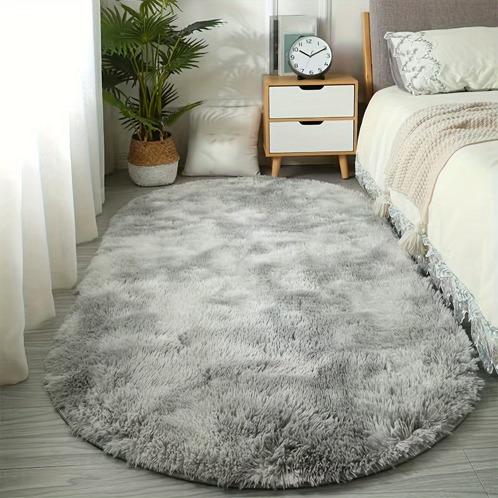 CloudLuxe ultra-soft plush rug in light gray, oval-shaped beside bed with wooden nightstand and potted palm - cozy bedroom setting