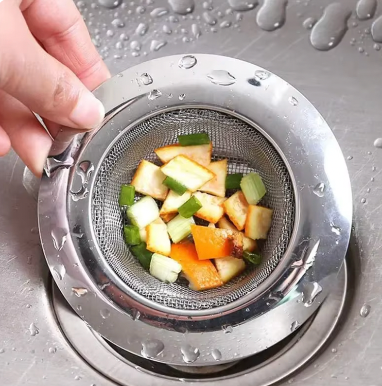 DrainShield stainless steel sink strainer catching colorful food scraps with water droplets on metal surface