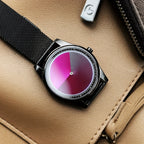 EclipseMotion watch with pink gradient dial and black mesh band on beige leather surface - modern minimalist timepiece
