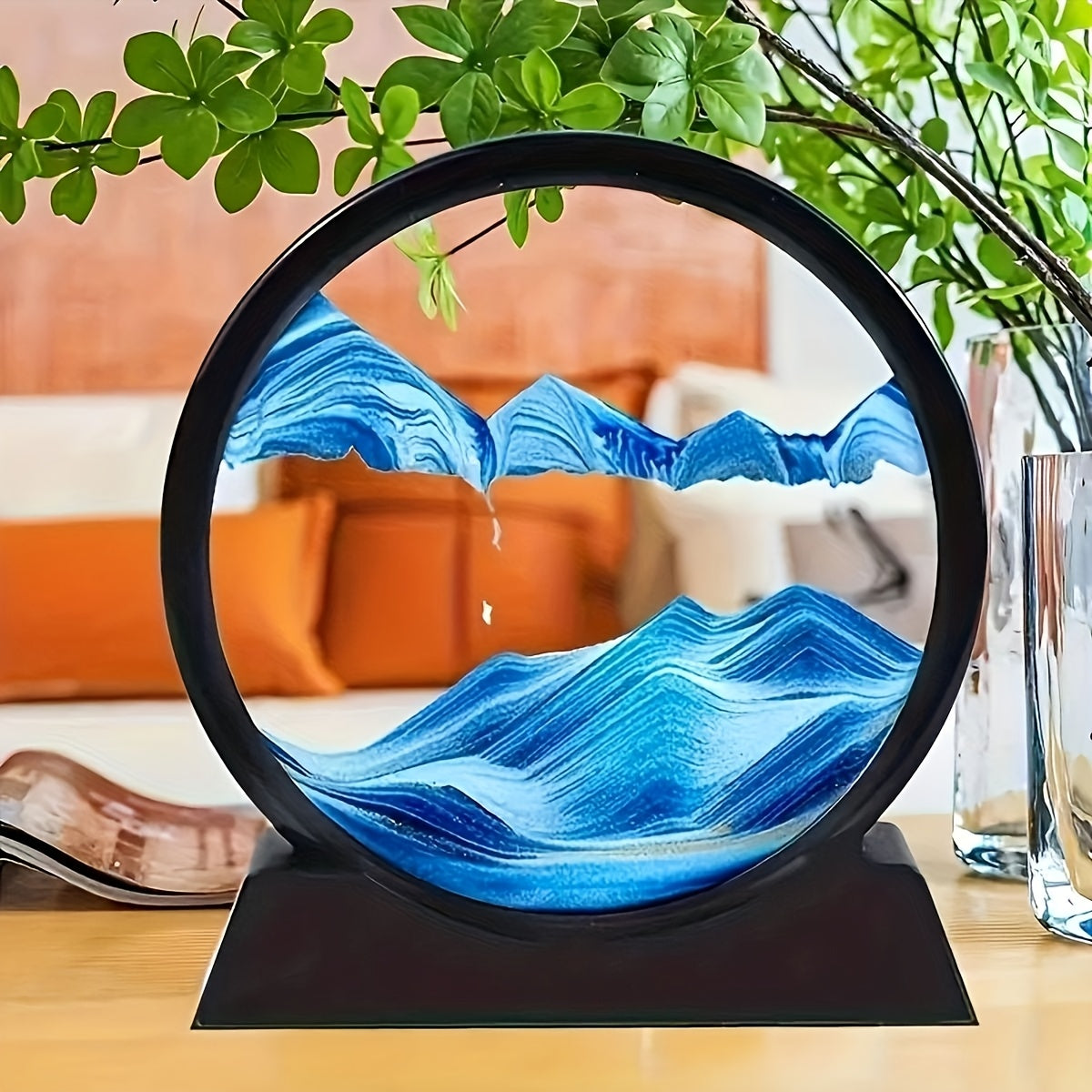 Eclipse Flow Dynamic Sand Art displaying blue flowing sand waves in circular black frame on wooden table with plants