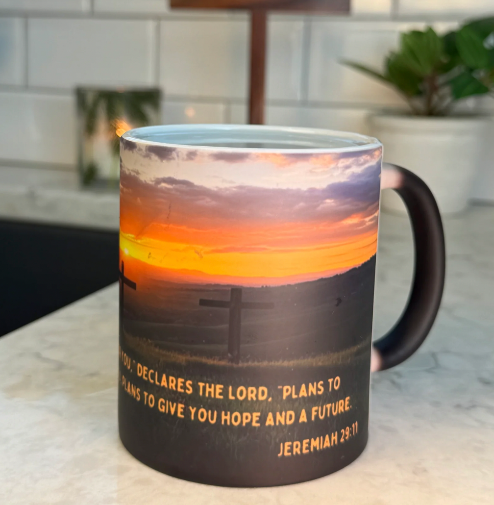 FaithGlow Mug featuring Jeremiah 29:11 verse on heat-reactive ceramic with sunset and cross design against marble countertop