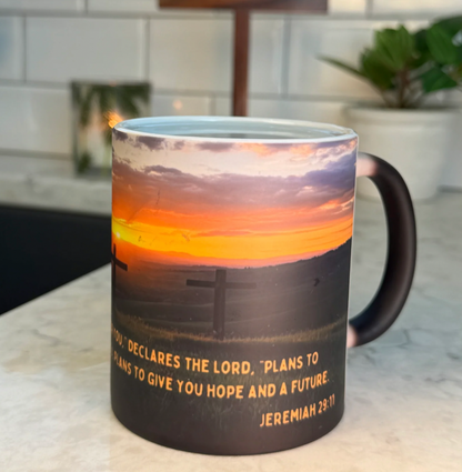 FaithGlow Mug featuring Jeremiah 29:11 verse on heat-reactive ceramic with sunset and cross design against marble countertop