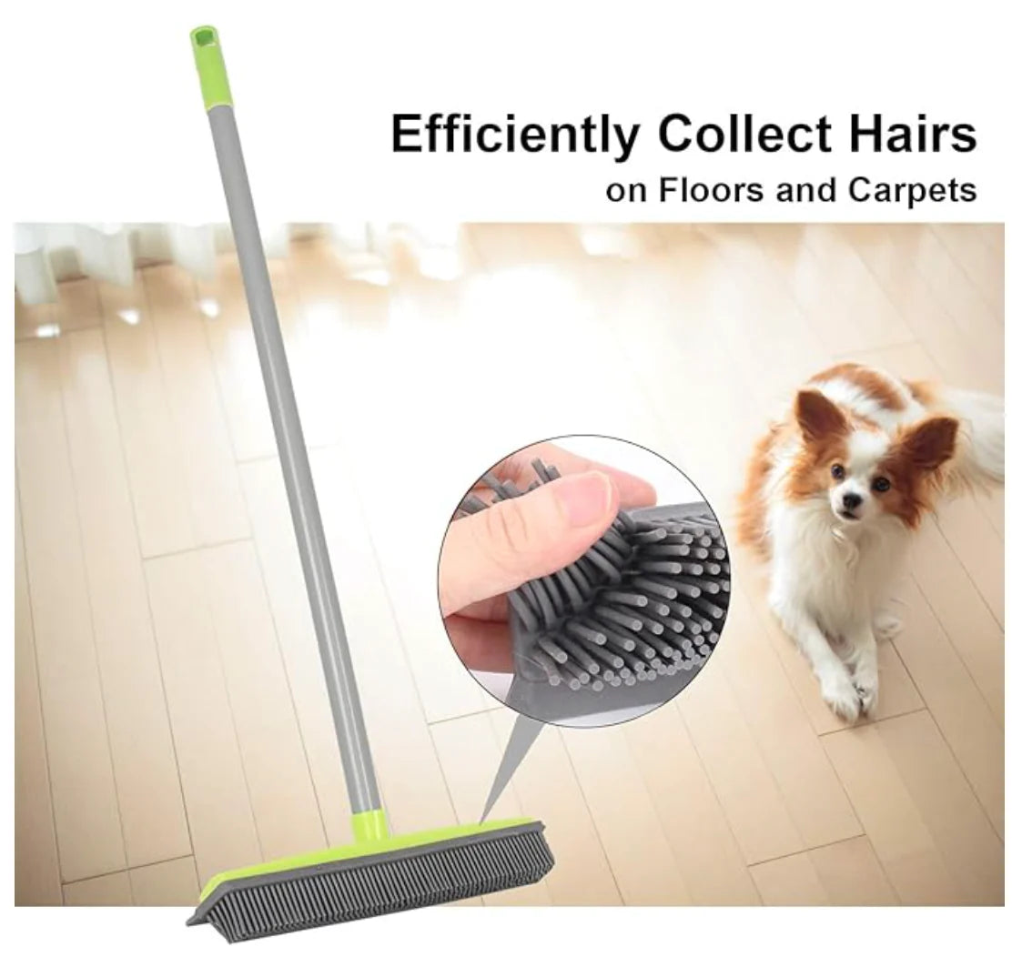 FurSweep Pro rubber bristle broom with grey handle and lime accents on hardwood floor beside small dog - pet hair cleaning demo