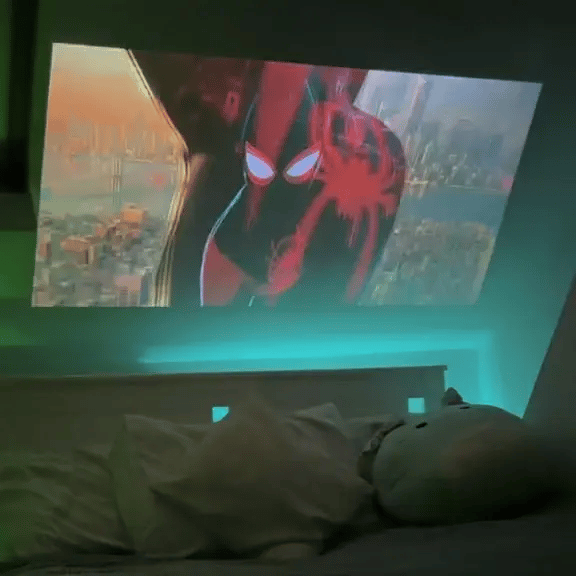 Get It All Bundle projector displaying animated content on ceiling with ambient green lighting in cozy bedroom setup