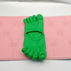 Giant Feet Slippers in bright green with realistic toe details on pink cushioned surface - novelty foot-shaped house shoes