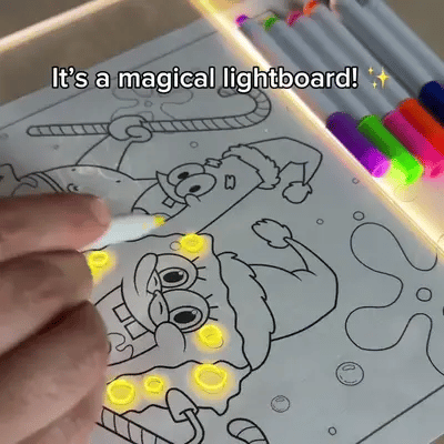 GlowSketch Board illuminating cartoon drawing with colorful markers, showing glowing yellow tracing effect on white surface
