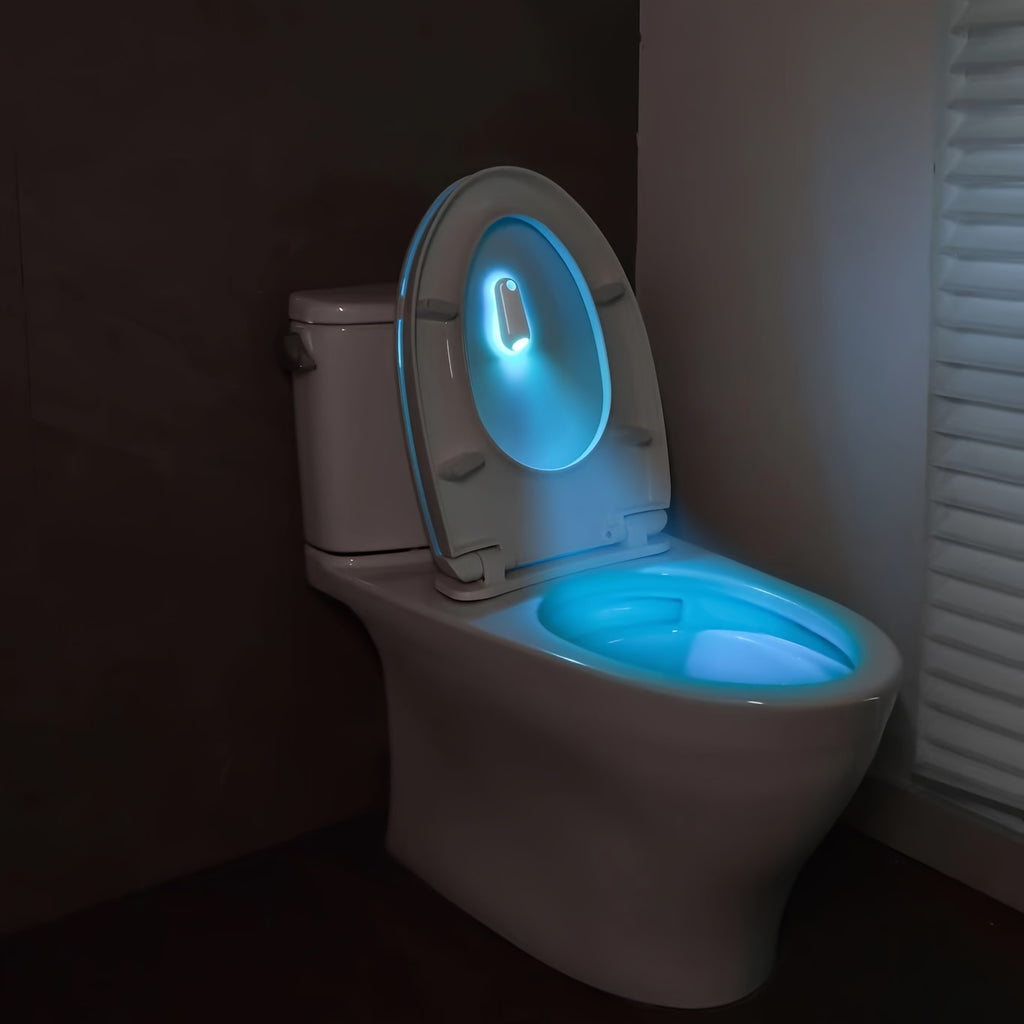 GlowStep Motion Sensor Light installed on toilet bowl rim, illuminating bright blue LED light in dark bathroom setting