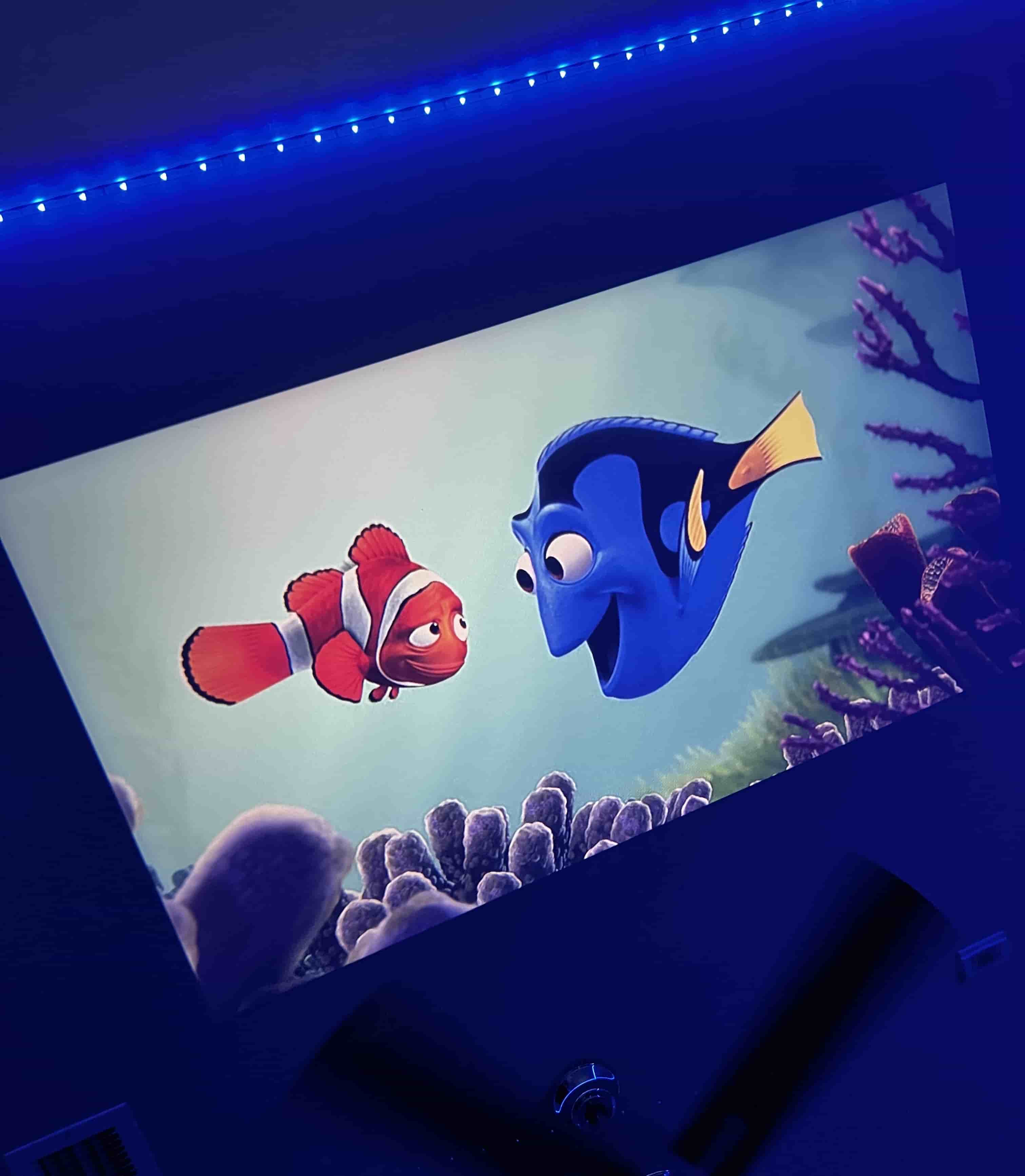 HighPeak MiniProjector displaying Finding Nemo movie scene with bright projection quality under blue LED ambient lighting