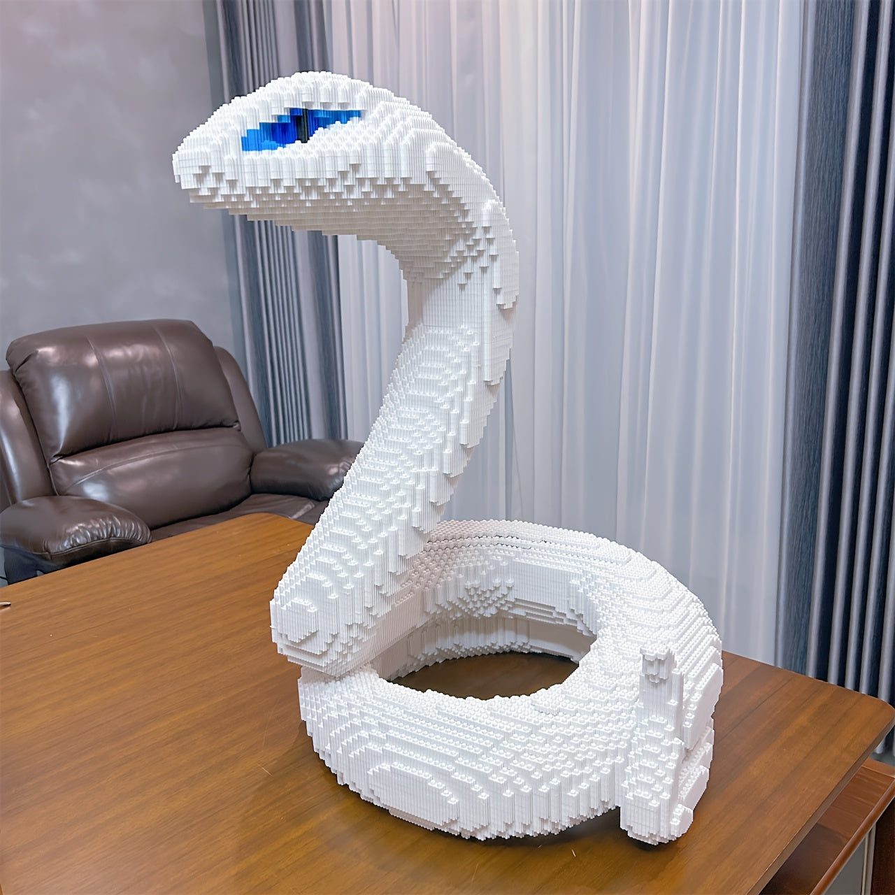 HighPeak SerpentMaster white coiled snake sculpture made from building blocks, with blue eyes on wooden table - display model
