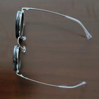 HighPeak ShiftLens sunglasses with silver frame and adjustable 9-in-1 lens system shown in side profile on wooden surface
