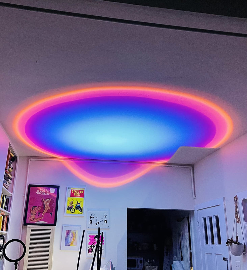 HighPeak Sunset Lamp projecting vibrant rainbow gradient circle on ceiling with blue center and pink-orange edges in room with art