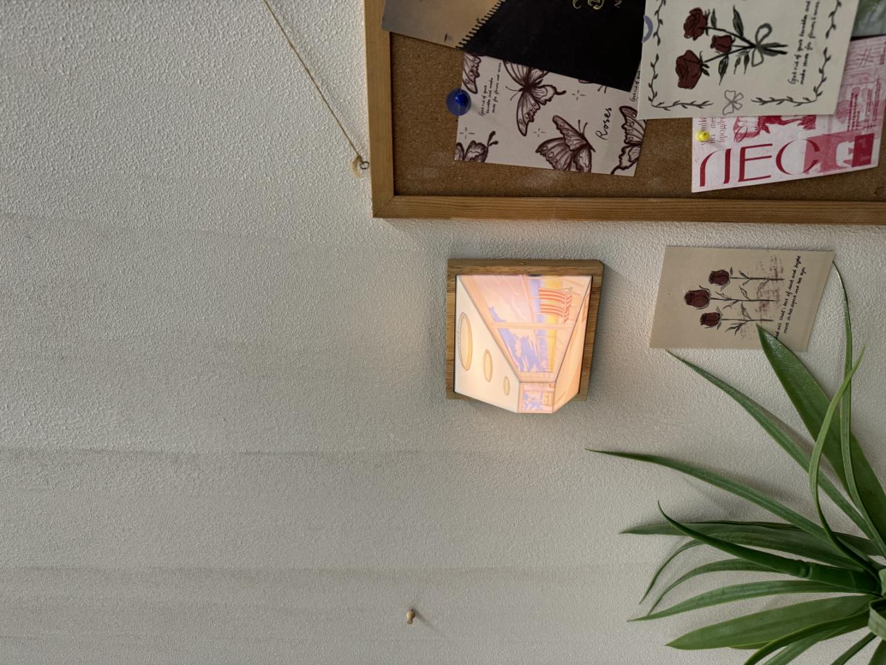 HighPeak Wallusion mounted on white wall with warm LED glow, creating 3D optical illusion next to indoor plant