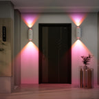 LumeGlow motion-sensing wall lights casting pink ambient glow around modern black door entrance with decorative plant
