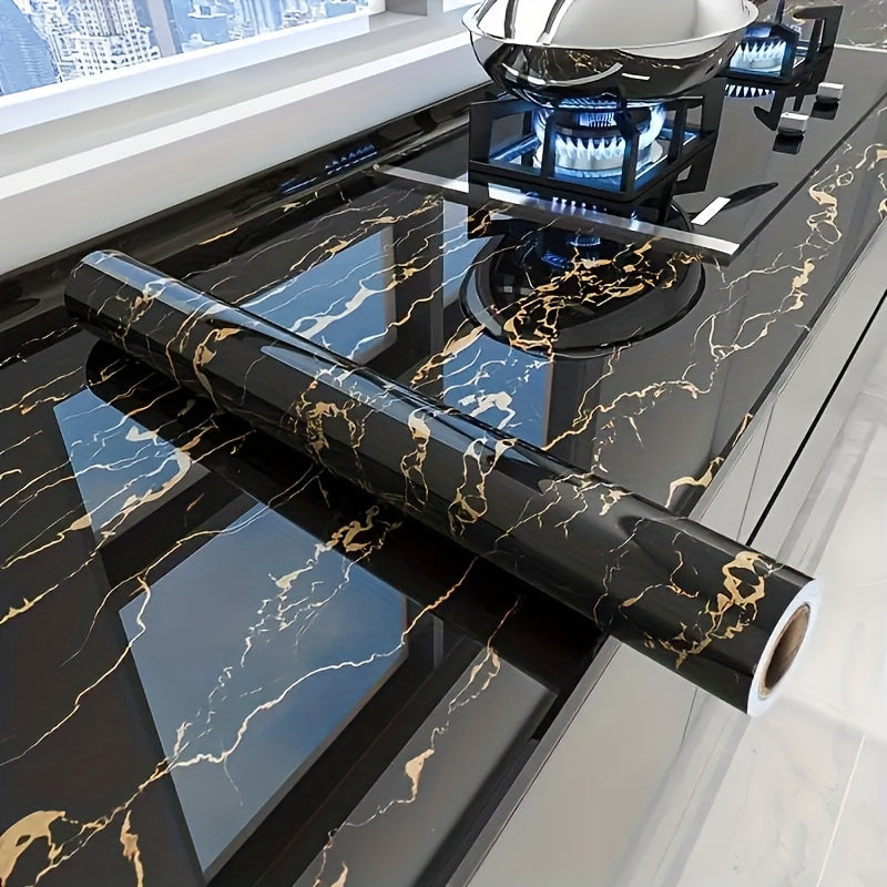LuxeMarble vinyl wrap roll displayed on black and gold marble countertop with gas stove - elegant kitchen renovation