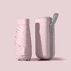 Mini Pocket Umbrella in pastel pink with matching hard case, folded compact design showing protective sleeve and carrying strap
