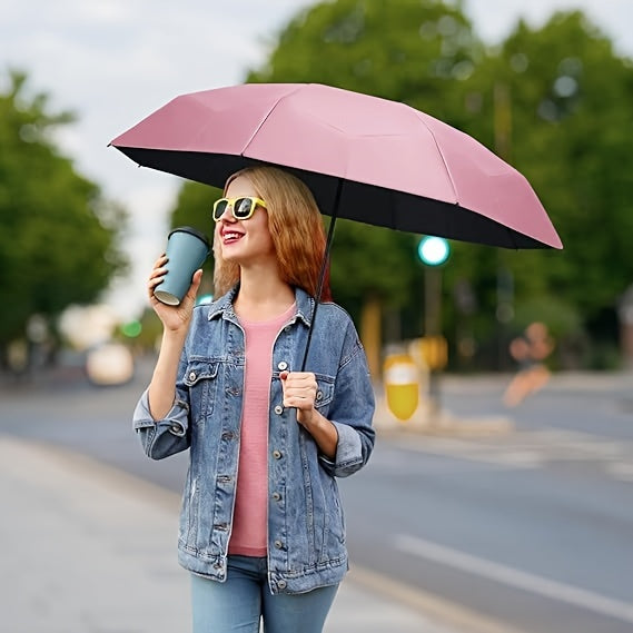 Mini Pocket Umbrella in pink shown open outdoors, providing stylish rain protection on an urban street with trees in background