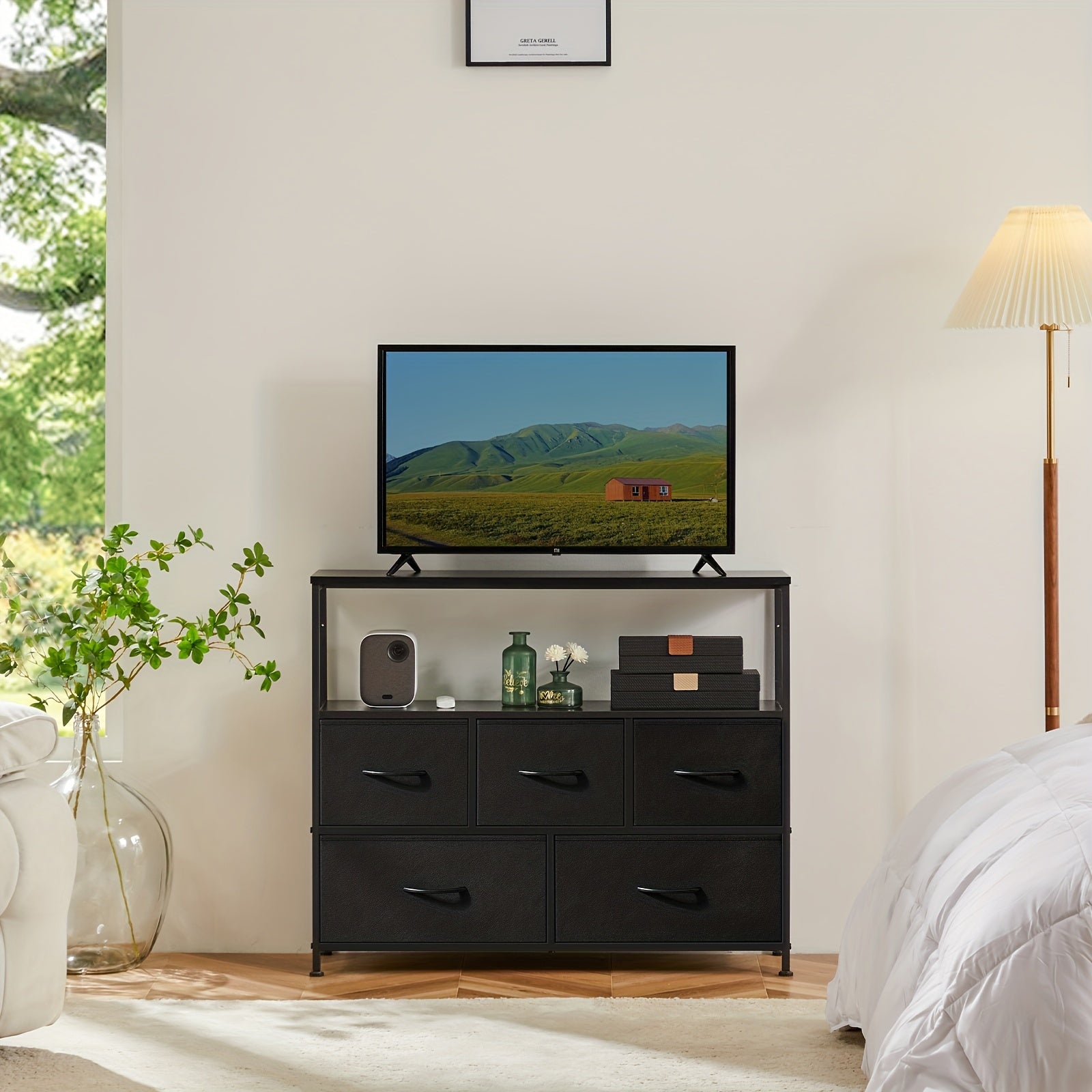 Modern black TV stand and dresser with 5 drawers and open shelf display in bright bedroom setting