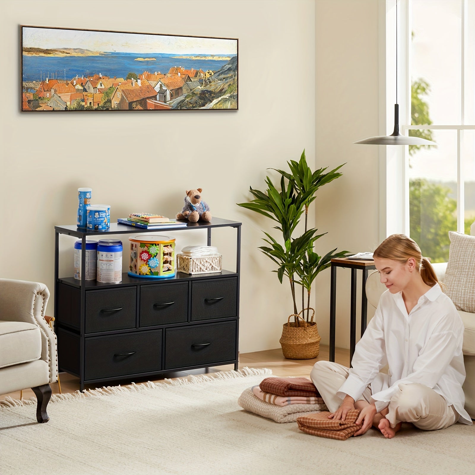 Modern black TV stand and dresser with 5 drawers and open shelf, displayed in cozy living room with potted plant