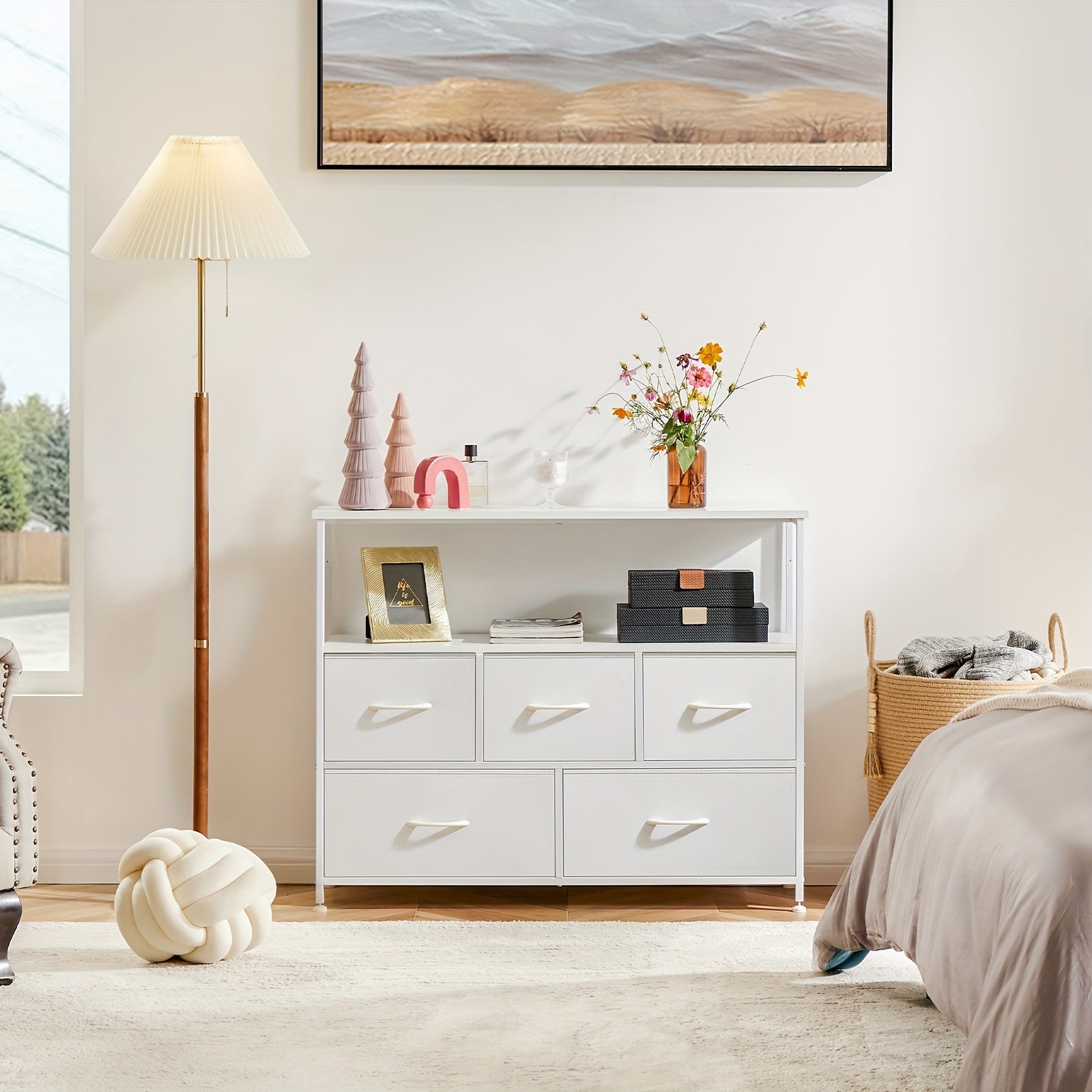 Modern white TV stand and dresser with 5 drawers and open shelf, styled in cozy bedroom setting with decorative accents