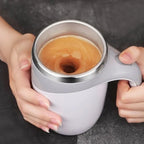 HighPeak Self Stirring Mug in white held with coffee mixing inside and stirring button visible on handle