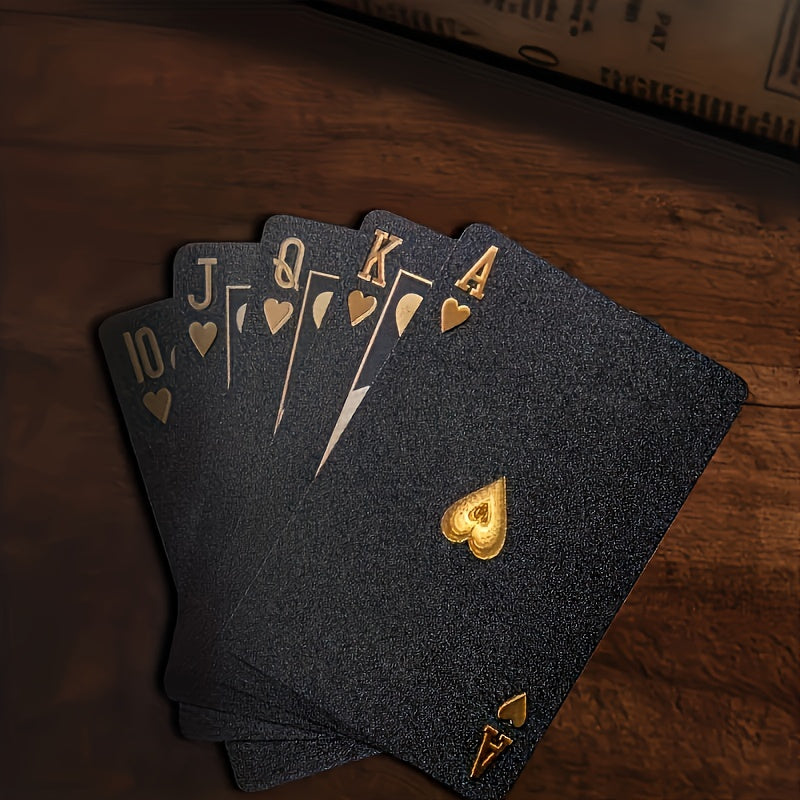 PrestigeDeck black playing cards with gold royal flush in hearts displayed on dark wooden surface - luxury poker cards