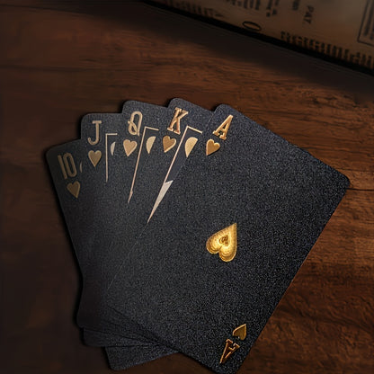 PrestigeDeck black playing cards with gold royal flush in hearts displayed on dark wooden surface - luxury poker cards