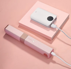 QuickStyle Pro wireless hair straightener in pink charging via power bank on pink surface - portable styling tool