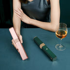 QuickStyle Pro wireless hair straighteners in pink and green shown on dark table with wine glass - portable styling tools