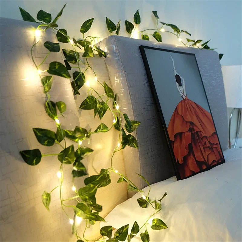 GlowVine Lights by HighPeak glowing warm ivy vines draped over a beige headboard with framed art.