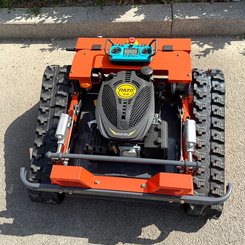 HighPeak Self-Driving Lawn Mower in orange with black tracked wheels and blue remote control on pavement outdoors