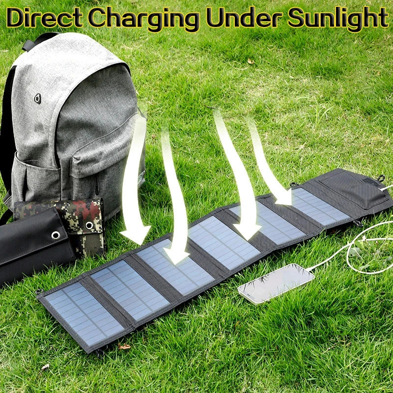 SunVolt Solar Panel unfolded on grass charging a phone under sunlight next to a gray backpack by HighPeak