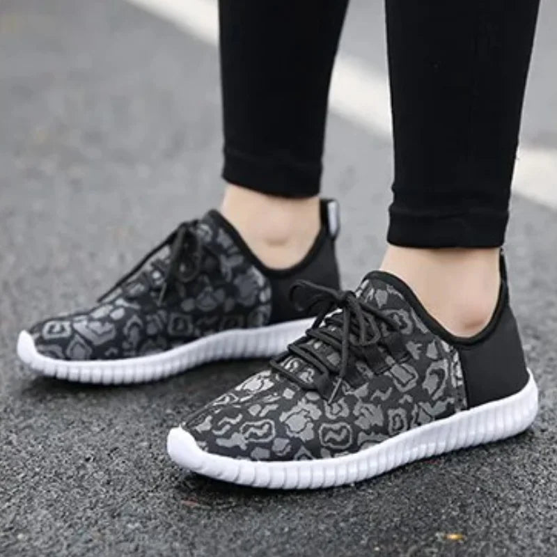 HighPeak Glowstride Sneakers in black and gray leopard print with white sole worn outdoors on asphalt
