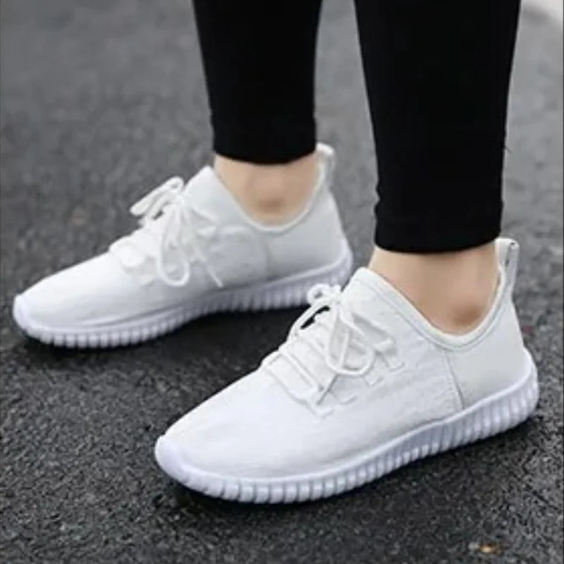 HighPeak Glowstride Sneakers in white with elastic sole and breathable upper worn outdoors on asphalt surface